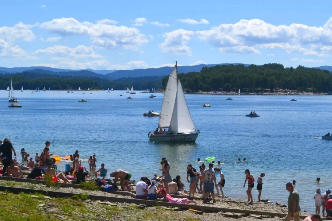 Ludzie na plaży oraz ł&oacute;dka na Jeziorze Solińskim