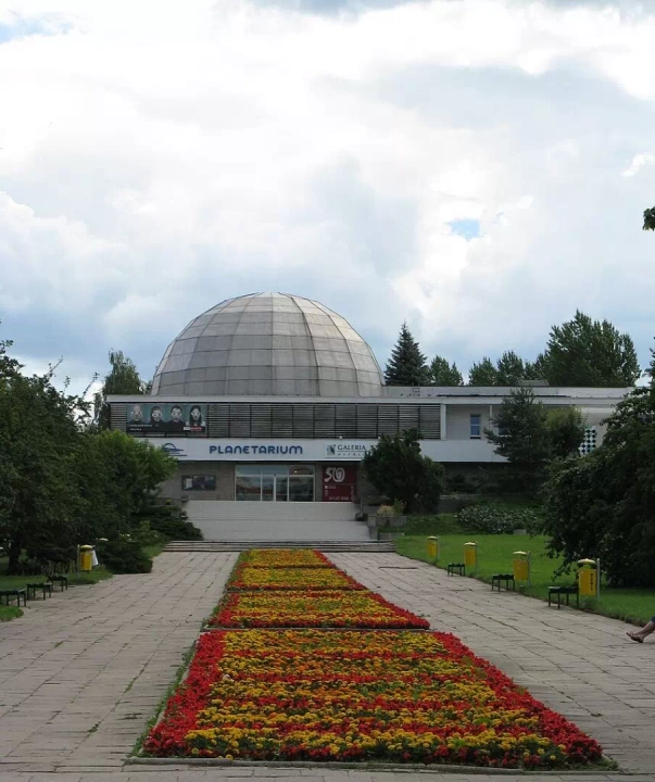 W samym Olsztynie można podziwiać cały kosmos za sprawą Olsztyńskiego Planetarium, kt&oacute;re widać na zdjęciu. Budynek ma imponującą kopułę, a przed jego wejściem rozciąga się dywan kwiatowy.