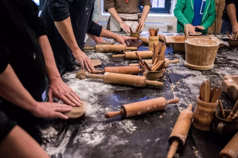 Grupa os&oacute;b, kt&oacute;ra odwiedza Muzeum Piernika w Toruniu i bierze udział w warsztatach z robienia piernik&oacute;w.